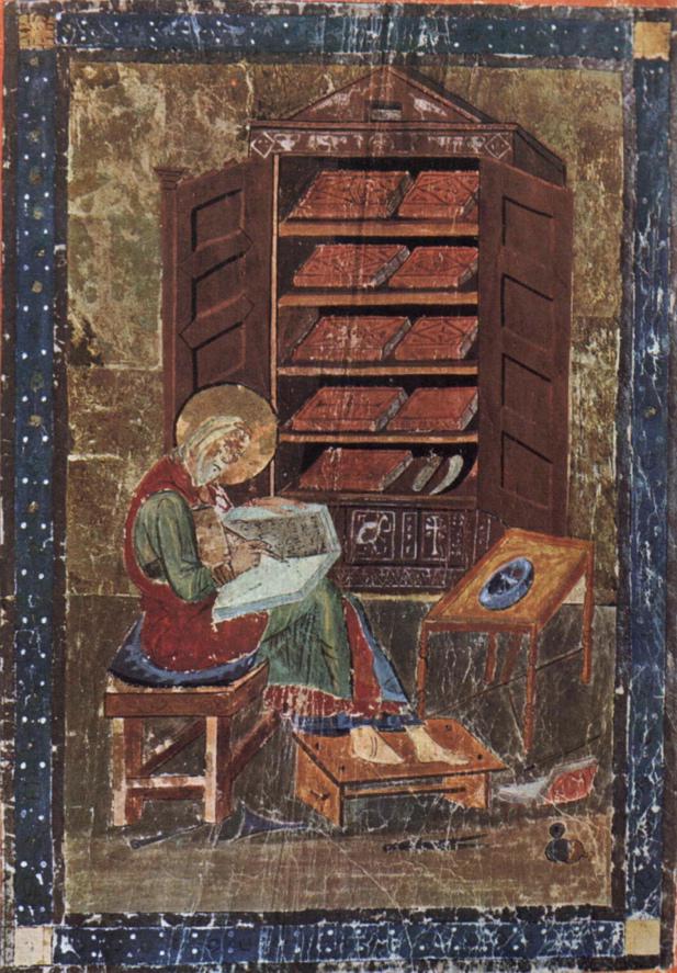  A medieval manuscript illustration showing a seated scribe, haloed and robed, working on a large open book. Behind the scribe is a cabinet filled with neatly arranged books or scrolls. A small table with a blue inkwell and quill rests to the right, and the scribe is engrossed in writing on a wooden desk.