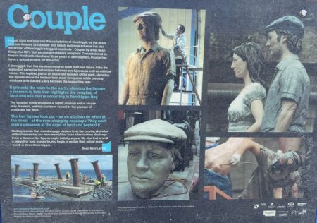 Informational board about the "Couple" sculpture in Newbiggin-by-the-Sea. It shows photos of the sculpture in different stages of creation, with images of the figures and artist Sean Henry at work. The text describes the background and meaning behind the sculpture, which represents the relationship between land and sea.