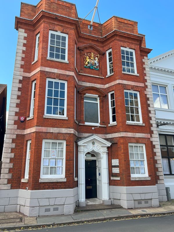 Harwich town hall - Red brick historical building in Harwich, UK, featuring large windows, a decorative coat of arms, and a classic white archway entrance