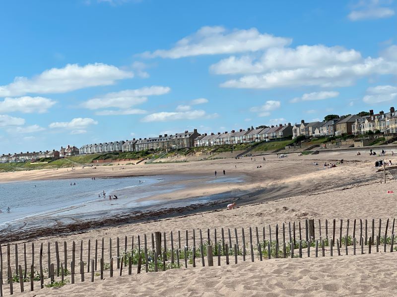 Newbiggin-by-the-Sea beach with sandy shoreline, sea, and houses in the background