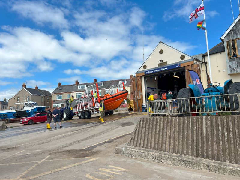 Lifeboat crew preparing an orange lifeboat at Newbiggin Lifeboat Station with tractors and equipment in the coastal town