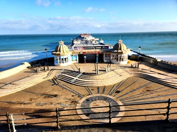 Cromer pier in Norfolk. Blue sky and sunny sky. showcasing the famous theathre and coastal promenade.