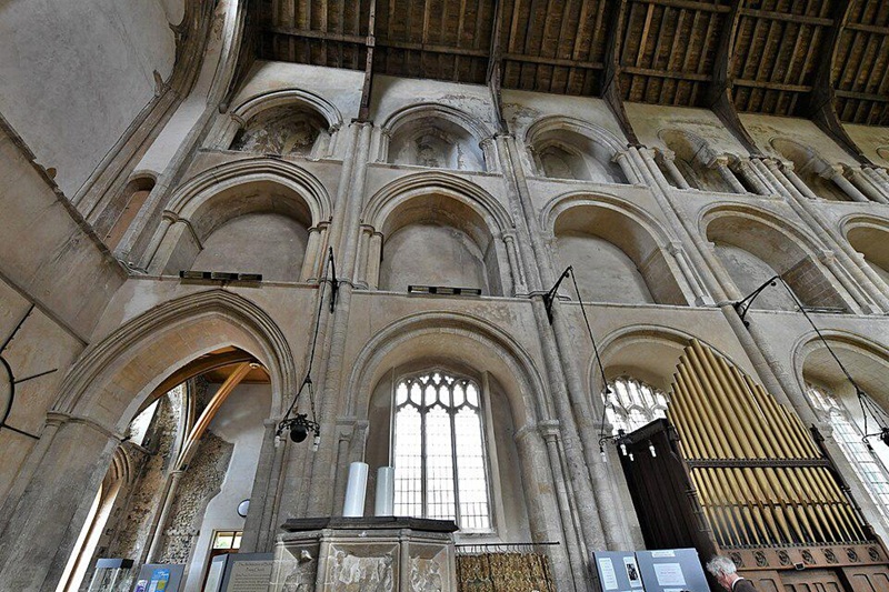Interior arcade and clerestory arches of Binham Priory Church in Norfolk, England, showcasing medieval Gothic architecture, stone columns, and historic church furnishings.