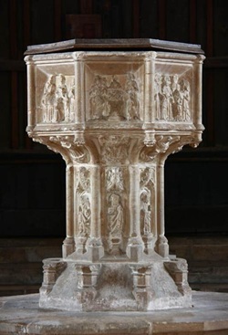 Medieval Seven Sacraments font at Binham Priory, Norfolk, England, featuring carved stone panels depicting Christian sacramental scenes.