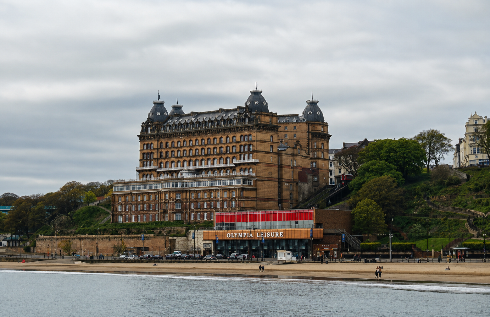 The Grand Hotel in Scarborough overlooking South Bay, with its ornate Victorian architecture, sandy beach, and the British coast beneath an overcast sky, a setting associated with Ann Brontë